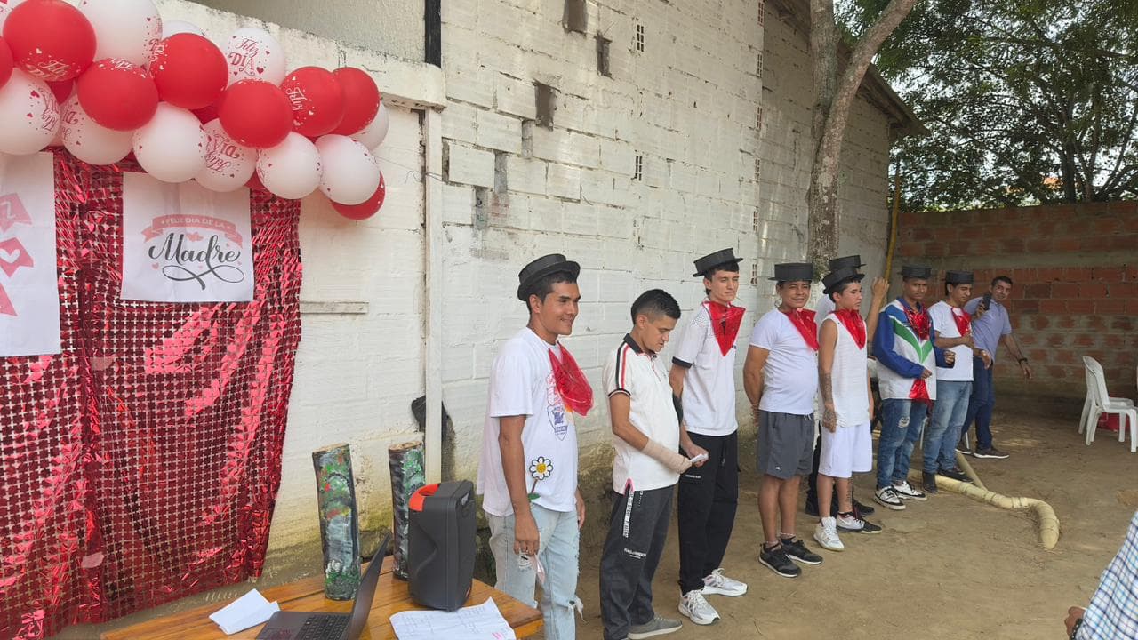 Participantes formados frente a una decoración del Día de la Madre durante una presentación